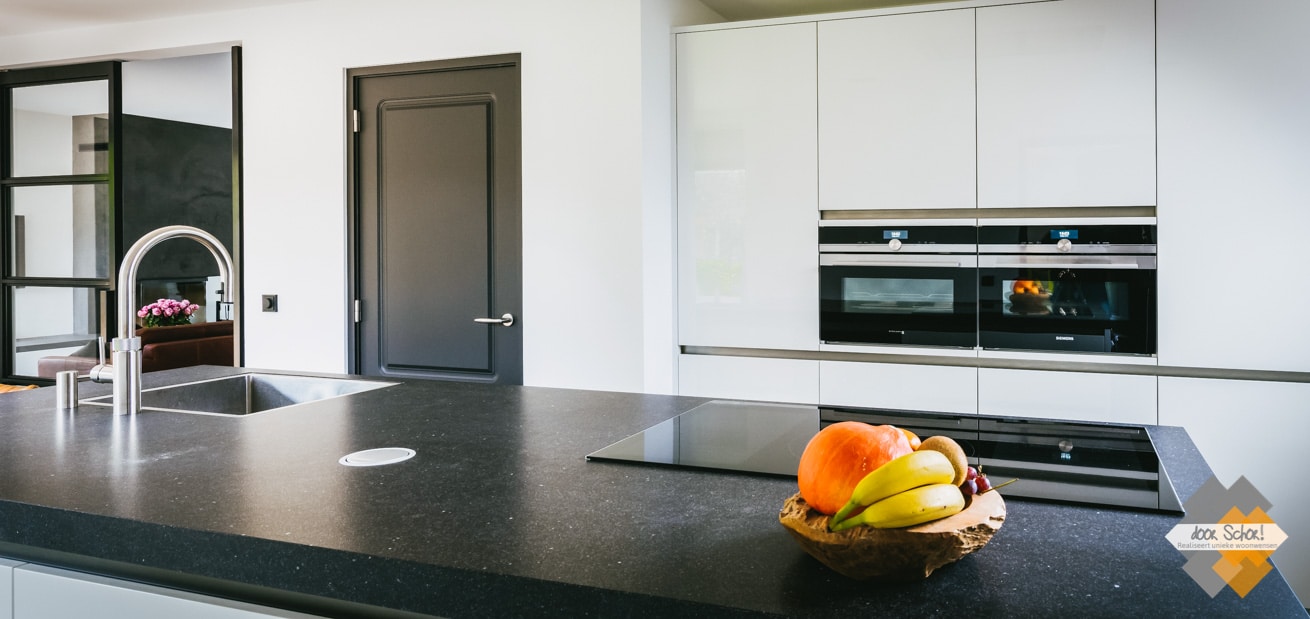 Dik granieten keukenblad met een mat witte keuken en fraaie donker grijze deuren